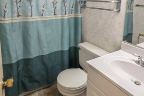 A bathroom with a toilet, sink, and shower curtain.