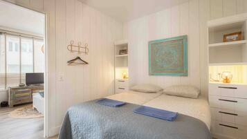 Une chambre à coucher comprenant un lit, des tables de chevet, une lampe suspendue et un élément décoratif fixé au mur.