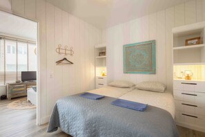 Ein Schlafzimmer mit Bett, Nachttischen, einer Hängelampe und einem Wandbild.