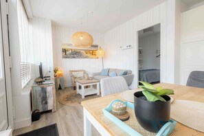 A modern living room with a sofa, coffee table, and a potted plant. - Top location! Next to lighthouse, beach 50m EBB (Egmond aan Zee)