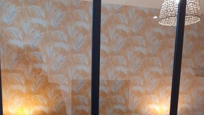 A bedroom with a bed, two bedside tables, and a wall with a leaf pattern. - KALEE Garden apartment (Lanester)