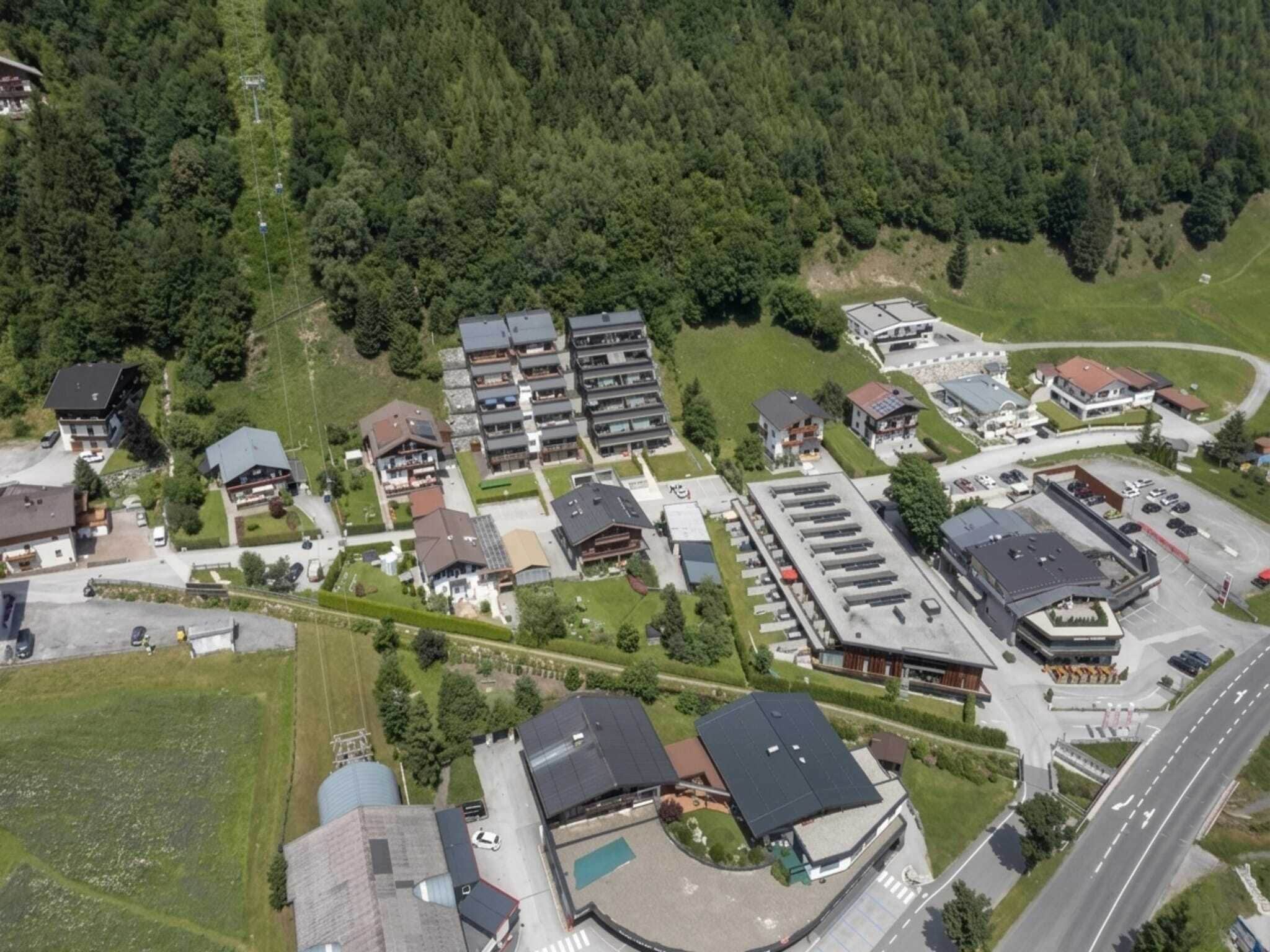 An aerial view of a residential area with multiple houses, a large building with a flat roof, and a road.