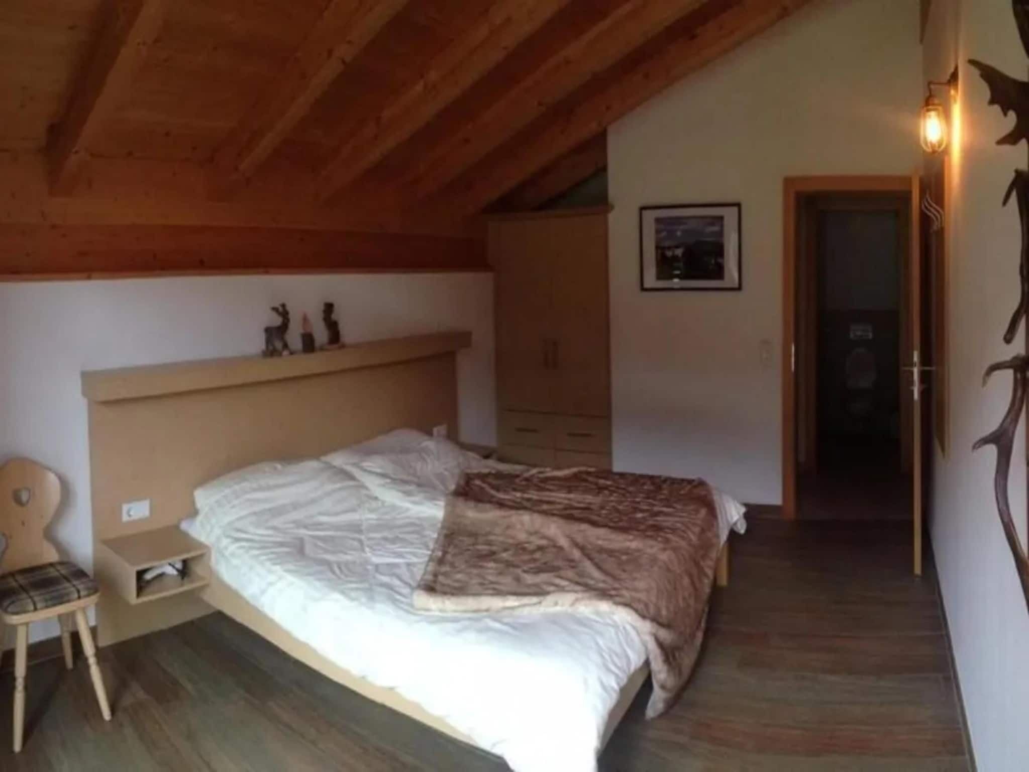Ein Schlafzimmer mit Holzboden, einem Bett, einem Nachttisch, einem Sessel und einer Kommode.