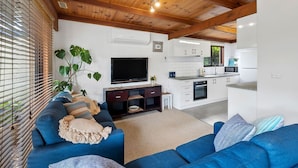 A modern living room with a blue sofa, a flat-screen TV, and a wooden ceiling.