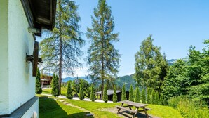 Un jardin avec une table de pique-nique, un chemin de pierres et un bâtiment à l’extérieur blanc.