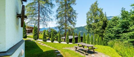 A garden with a picnic table, stone pathway, and a building with a white exterior.