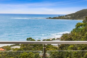A coastal view with a clear sky, a pier extending into the sea, and a residential area with houses and greenery. - Summerhills House (Lorne)