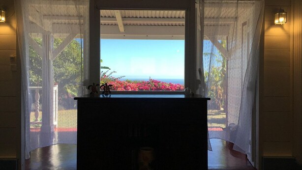 Ein Zimmer mit Blick durch ein Fenster, einem Holztisch und einem kleinen Tisch mit einer Vase.