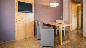 Et moderne spiseområde med et træbord og stole, et ophængt fjernsyn og en pendel.