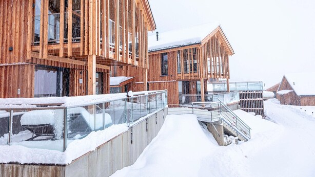 Un bâtiment en bois doté de grandes fenêtres et d’une allée couverte.