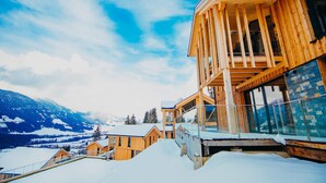 Un chalet en bois doté d’un balcon donnant sur un paysage montagneux enneigé.