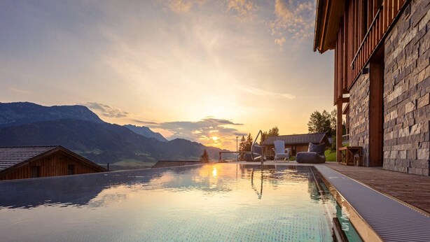 Une piscine avec vue sur les montagnes et sur le coucher de soleil.