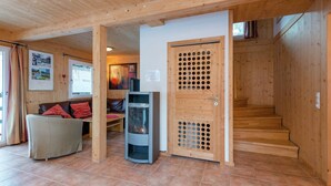 Ein Holzinnenraum mit Kamin, einer Couch und einer Treppe.
