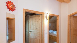 Eine Holztür führt in ein Schlafzimmer mit einem Bett und einem Nachttisch.
