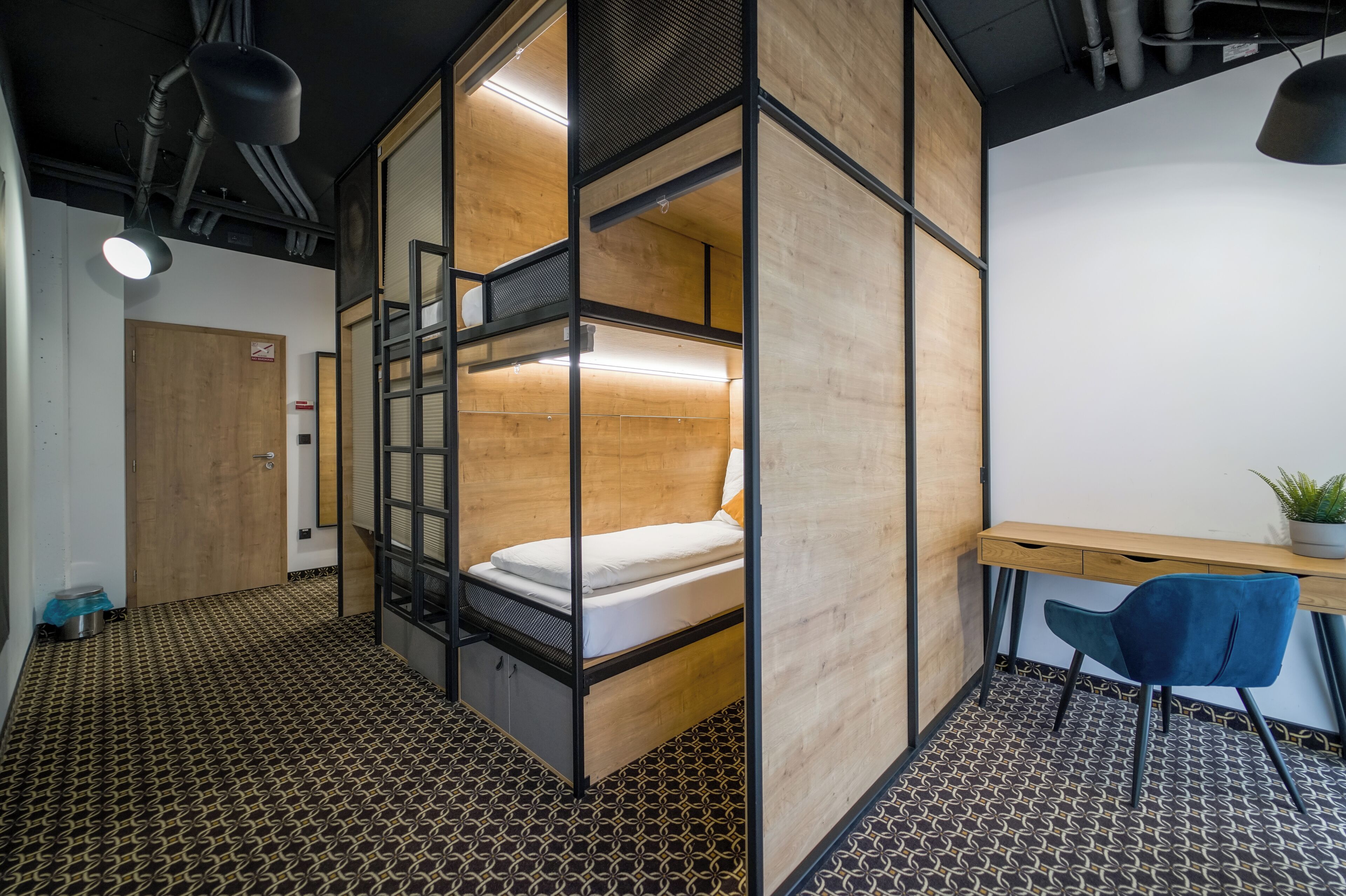 A compact, modern room with a bunk bed, a desk, and a chair.