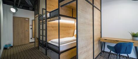A compact, modern room with a bunk bed, a desk, and a chair.