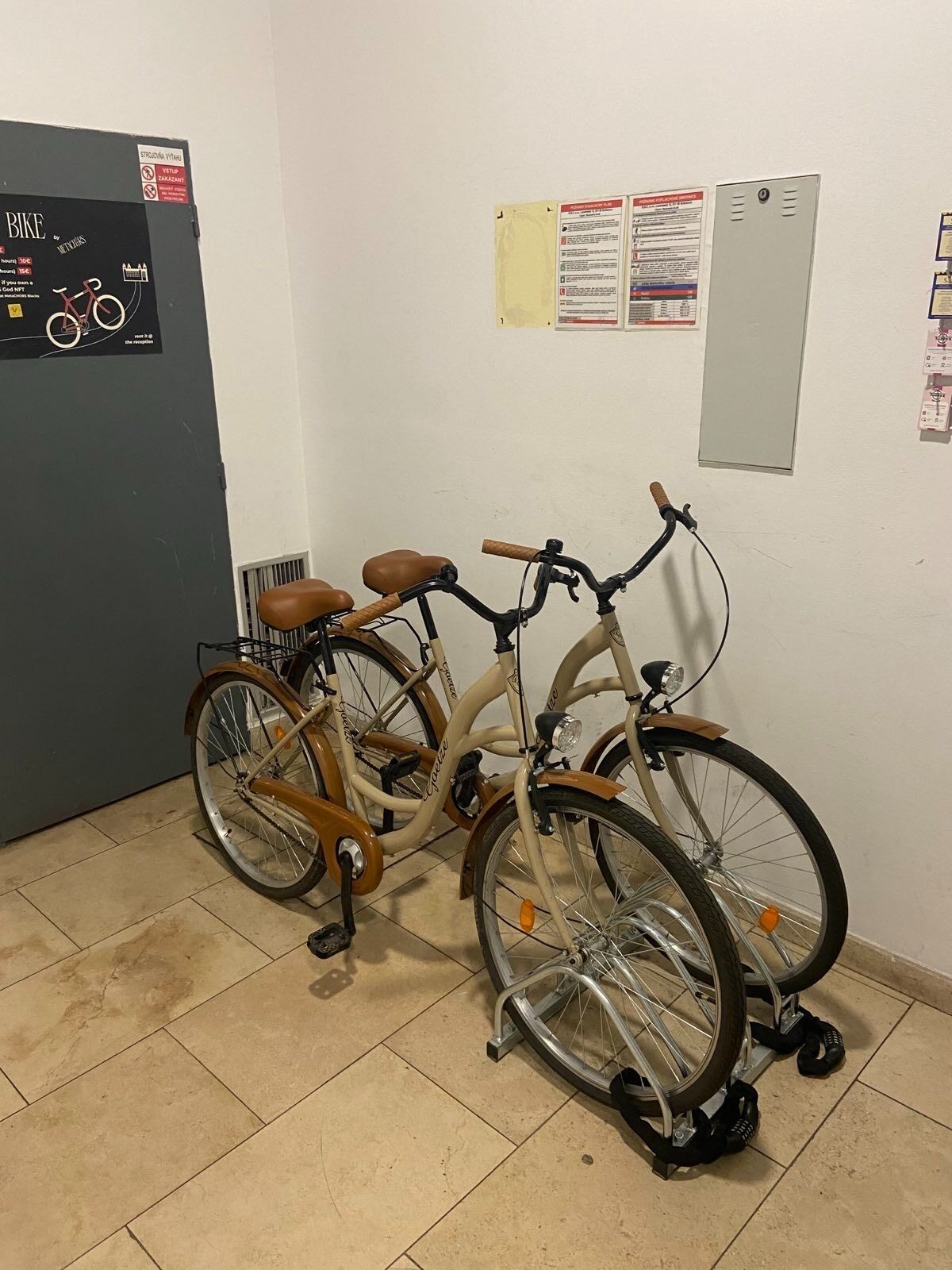 A bicycle with a brown seat and handlebars leaning against a wall in a room with tiled flooring.