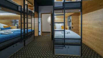 Habitación con literas, suelo estampado, paredes de madera y una pequeña planta en un estante.