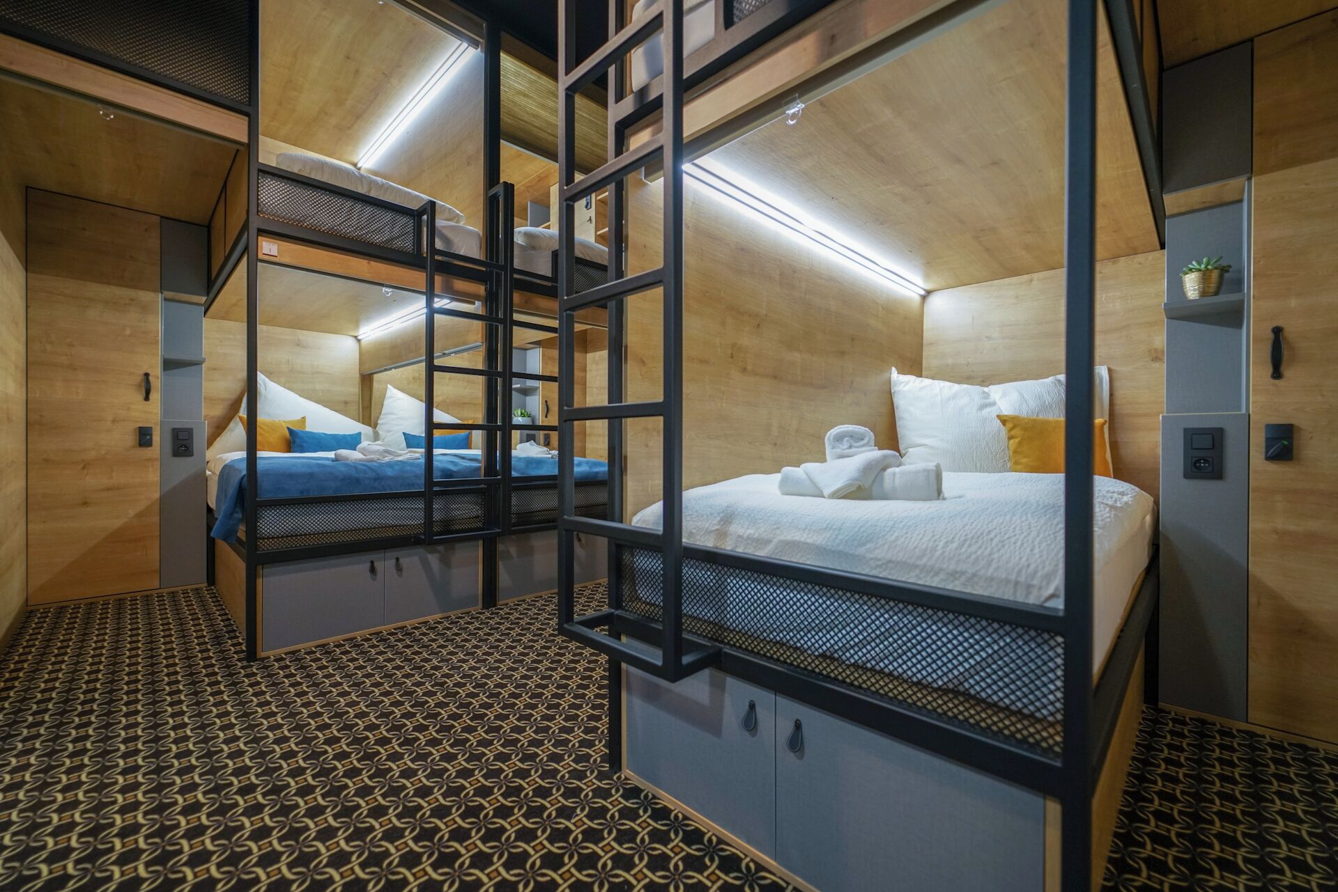 Una habitación de hotel pequeña con literas, piso estampado y paredes de madera.