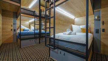 Una habitación de hotel pequeña con literas, piso estampado y paredes de madera.