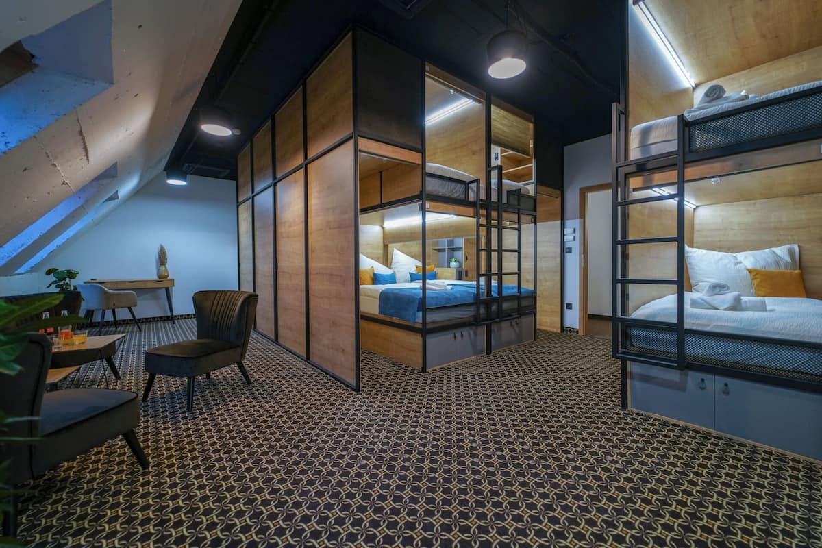 A modern, compact room with a loft bed, a desk, and a chair.