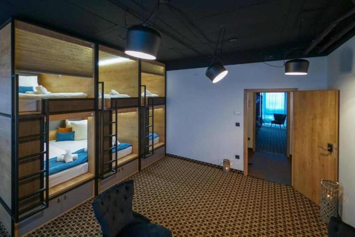A room with bunk beds, a patterned carpet, and a door leading to another room.