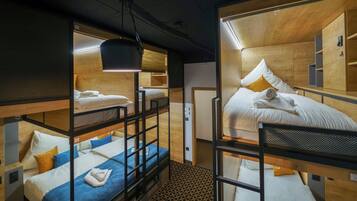 A compact hotel room with bunk beds, a small desk, and a mirror.