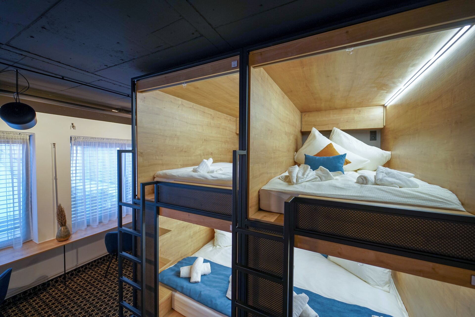 A bunk bed room with wooden walls and a window with blinds.
