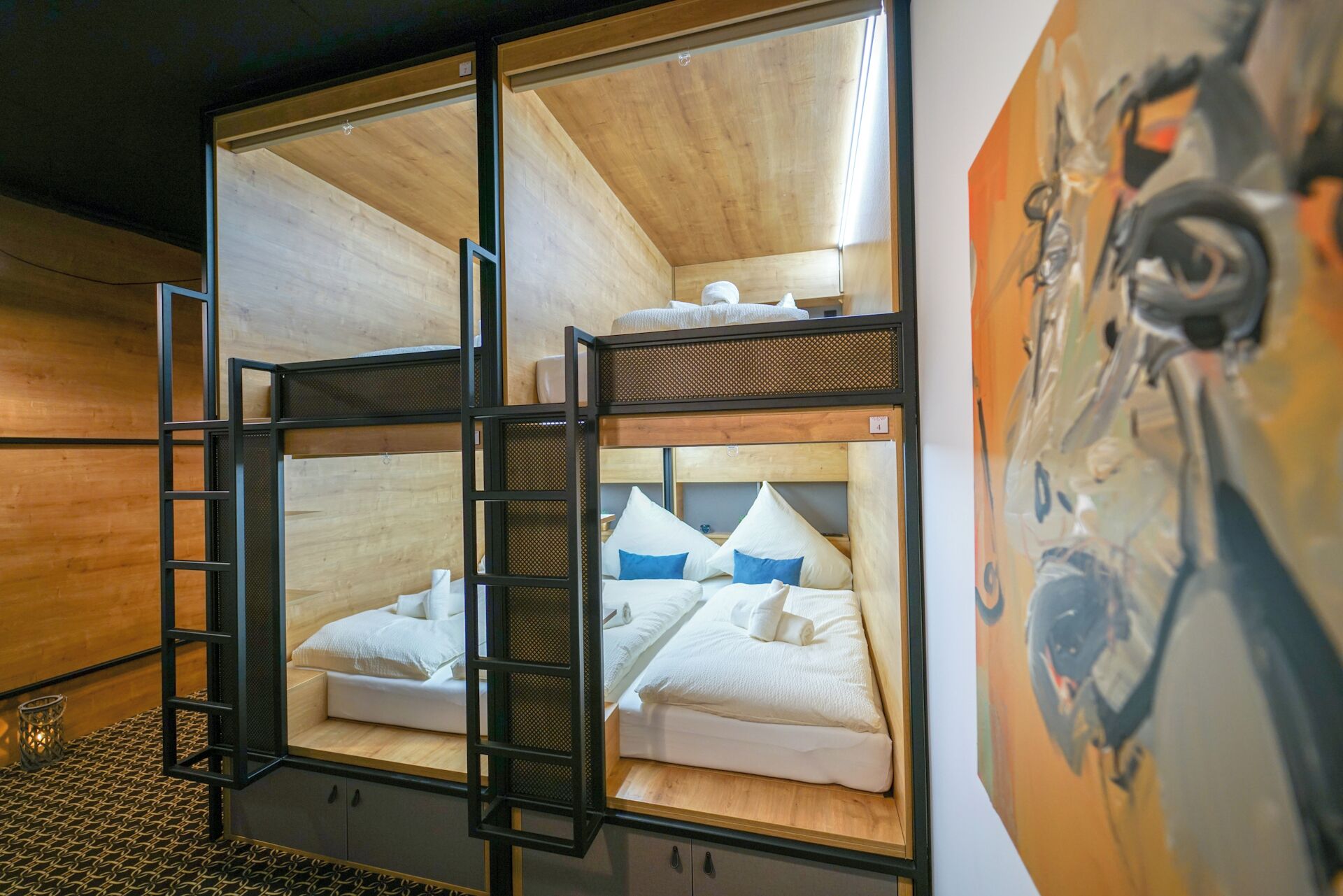 Habitación con literas, una mesita pequeña y un cuadro en la pared.