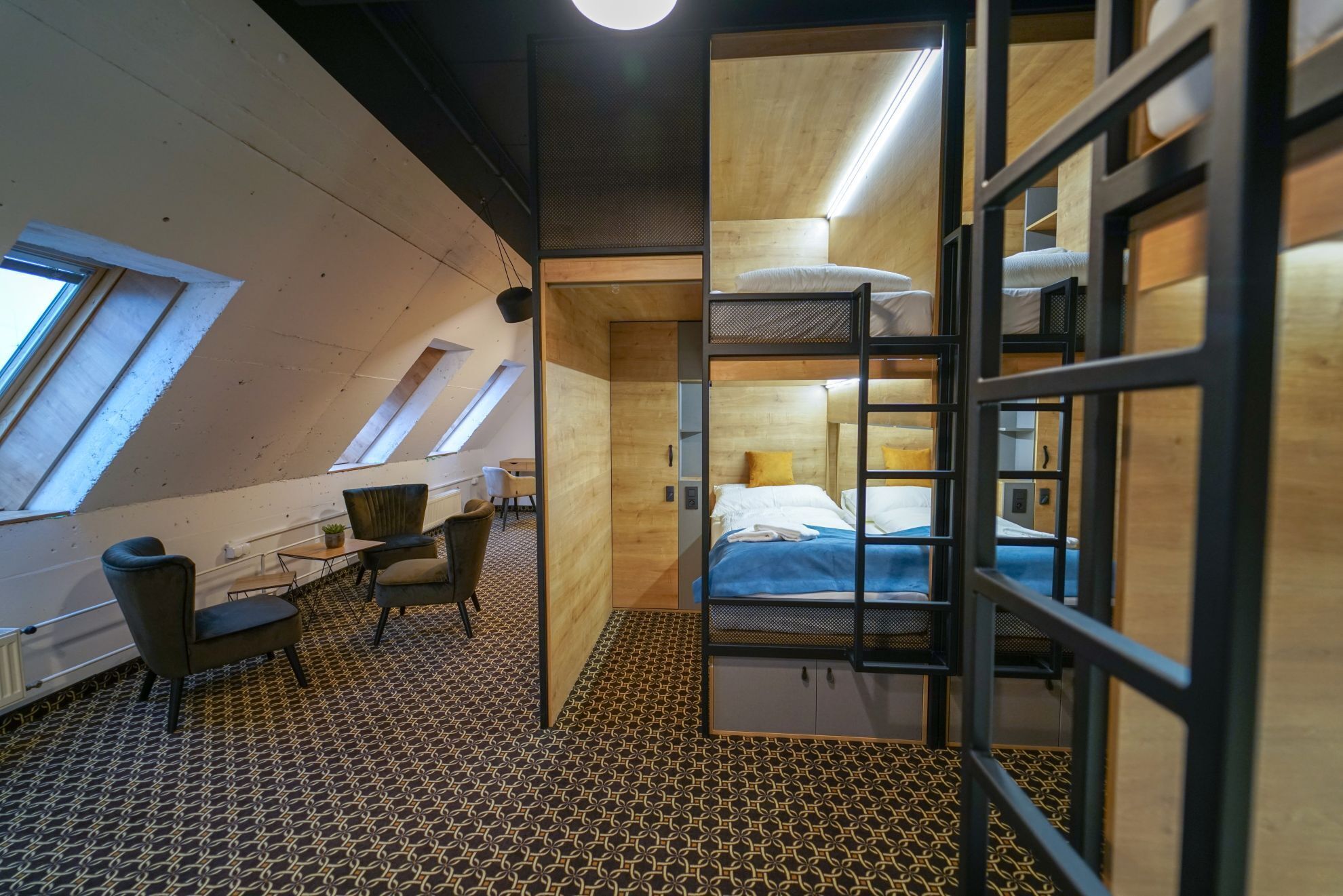 A compact, modern room with a sloped ceiling, a bunk bed, a desk, and a chair.