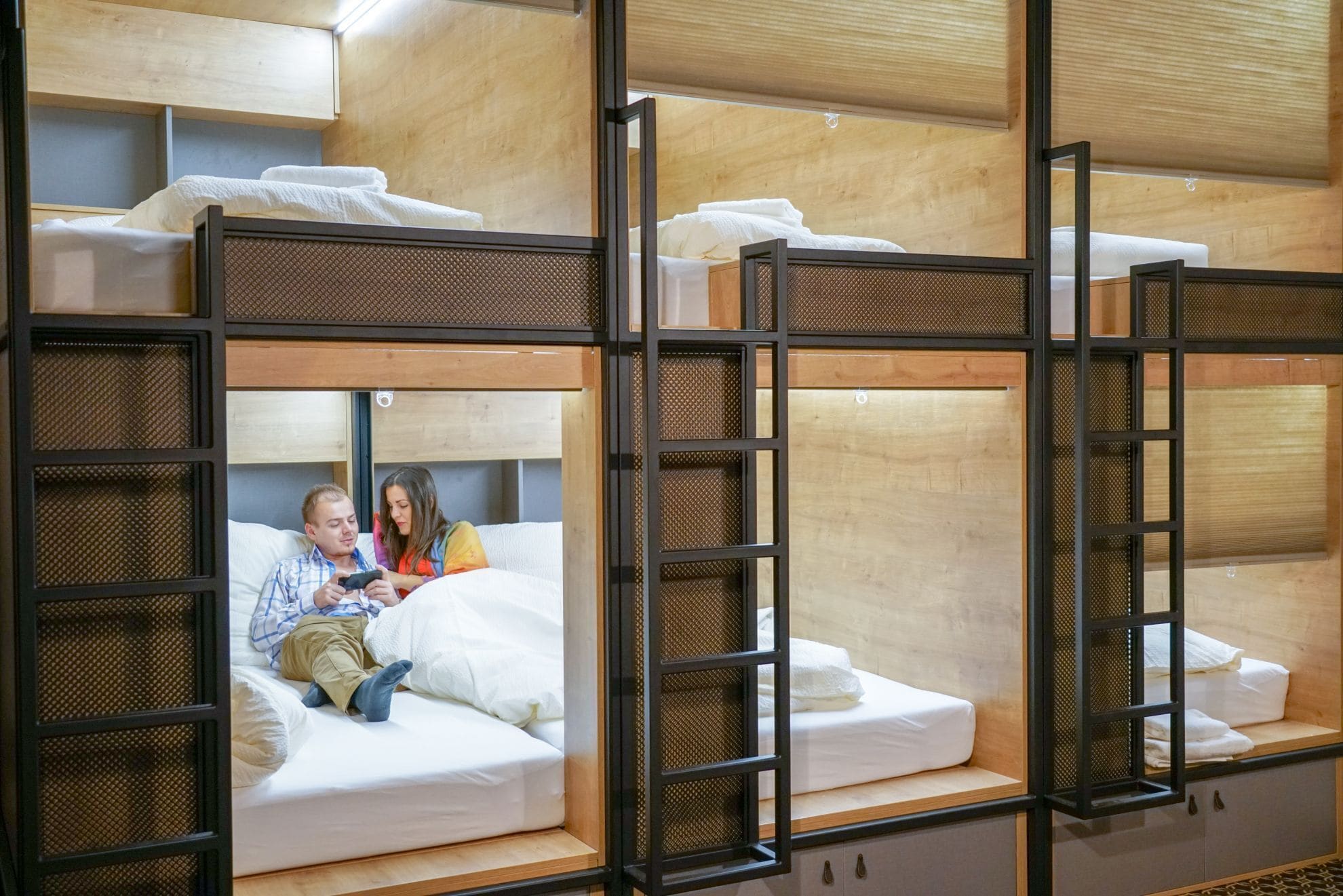 Bunk beds with a wooden frame and mesh panels, a sofa with cushions, and a small cabinet.