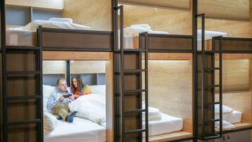 Bunk beds with a wooden frame and mesh panels, a sofa with cushions, and a small cabinet.