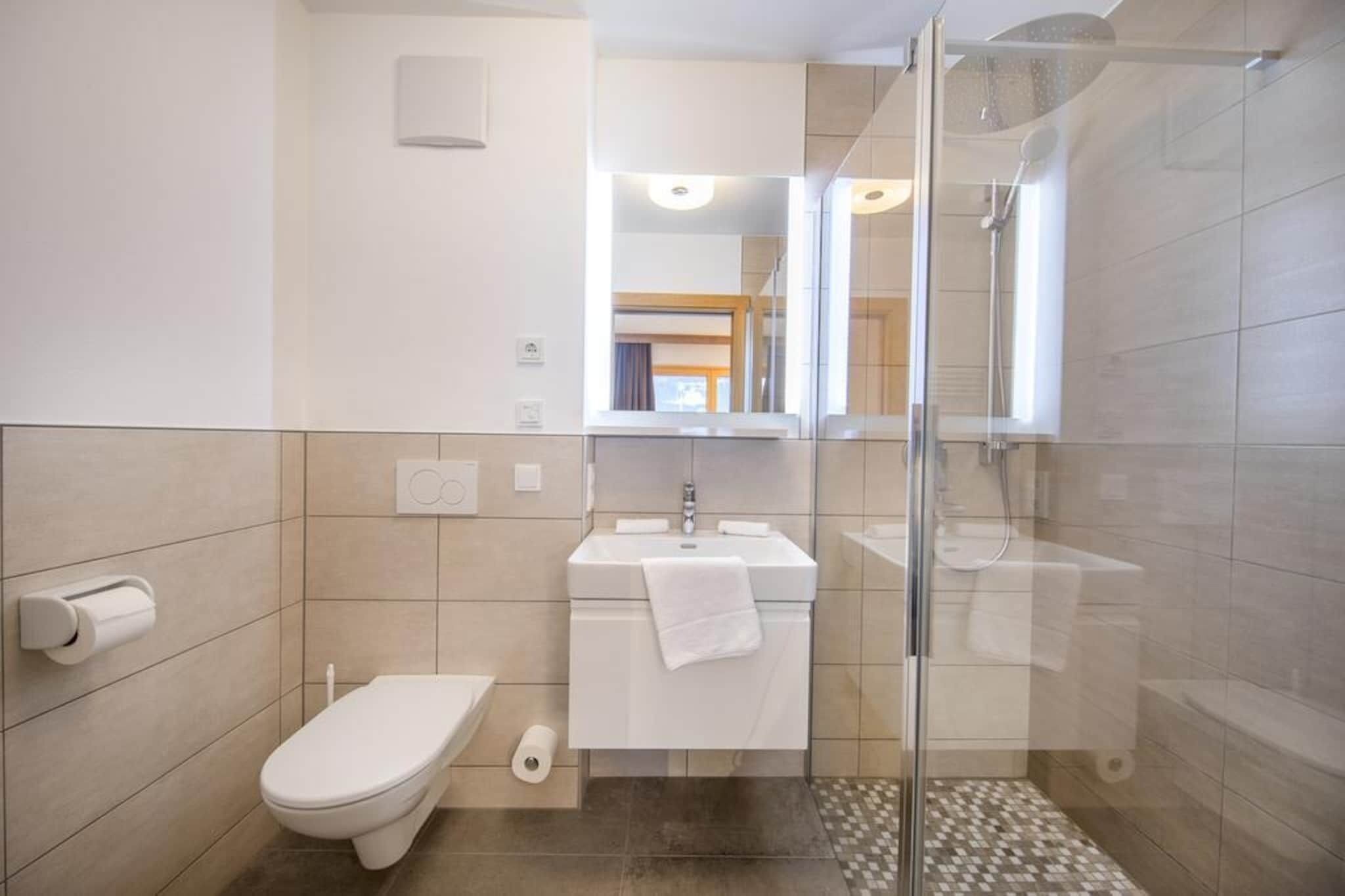 A modern bathroom with a toilet, sink, and glass-enclosed shower.