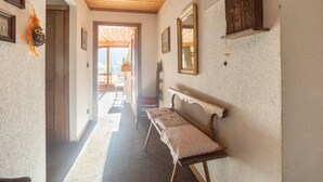 Un pasillo con un banco de madera, cuadros enmarcados y un espejo en la pared.