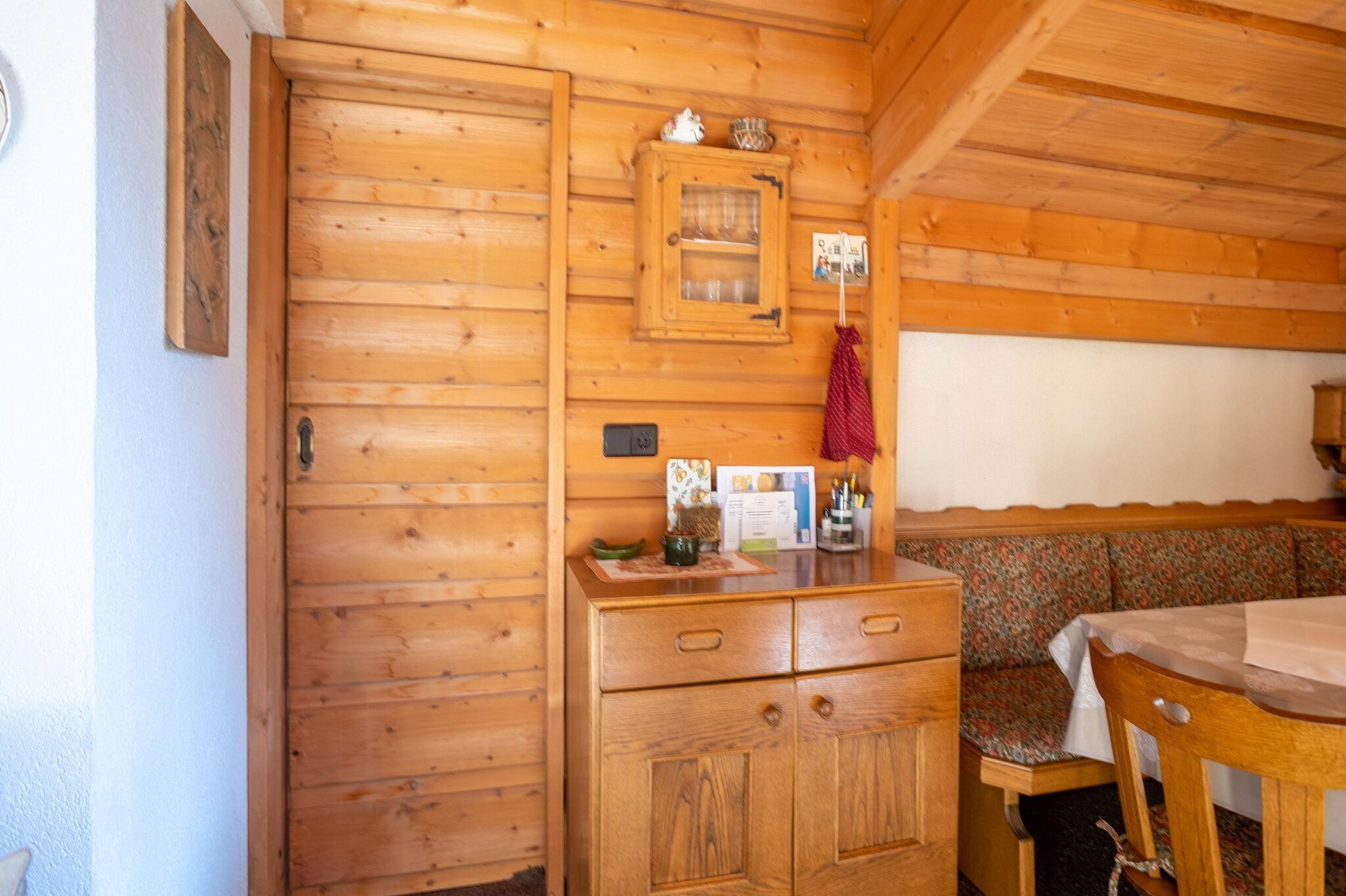 L’intérieur d’une cabane en bois, avec un meuble en bois, un banc et une table.