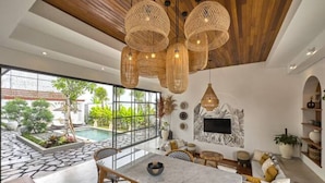 A spacious living area with a large window, a dining table, and a pool view. - Good Vibe Villa - 3 Bdrm Luxury Villa (Canggu)