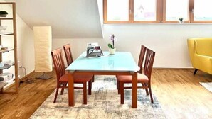 Uma sala de jantar com uma mesa, cadeiras, uma luminária e uma janela com vista.