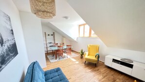 Um apartamento loft moderno, com área de jantar, uma poltrona amarela e um sofá azul.