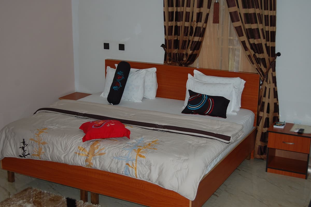 Ein Bett mit hölzernem Gestell, weißer Bettwäsche und Zierkissen.
