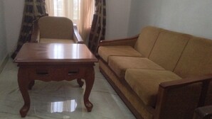 A living room with a wooden coffee table and a sofa. - Nue Crest Hotel & Suites (Enugu)