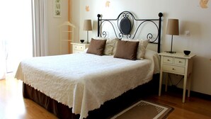 A neatly made bed with a white bedspread and brown pillows, flanked by two bedside tables with lamps, in a room with wooden flooring and a decorative rug. - Presley Beije Apartment, Quinta do Lago, Algarve (Algarve)
