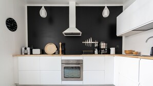 A modern kitchen with white cabinets, a stainless steel oven, and a black backsplash. - Luminous 1br next to Puu-Vallilla (Helsinki)