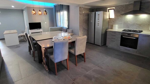 Cocina moderna con comedor, que incluye una mesa grande, sillas, refrigerador, horno y estufa a gas.