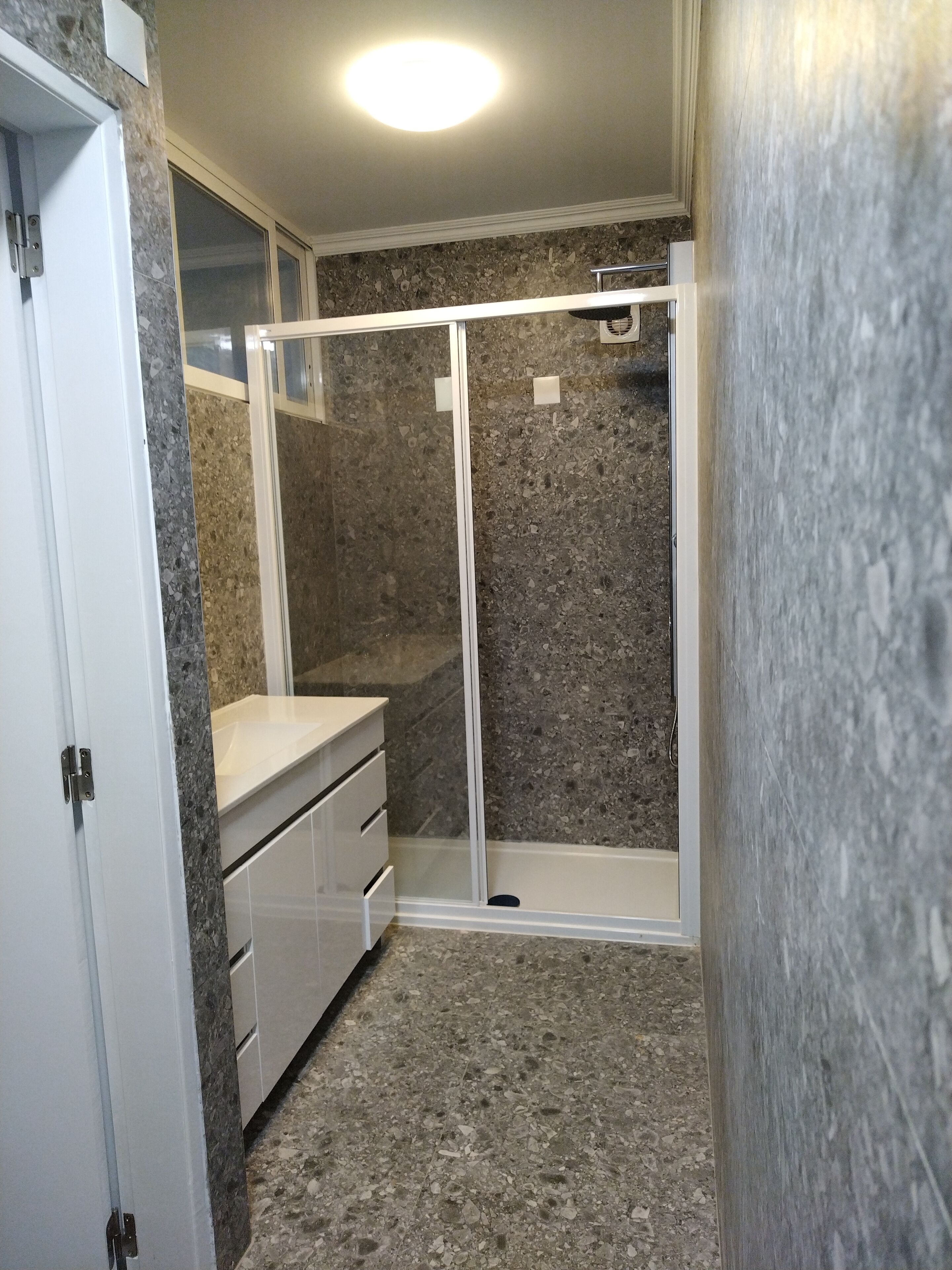 A bathroom with a shower, a sink, and a cabinet.