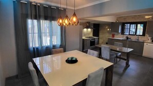 Un comedor moderno con una mesa grande y sillas, una cocina al fondo y un diseño de techo original.