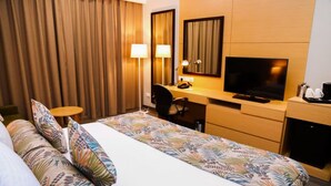 A hotel room with a bed, a desk with a television, a chair, and a coffee maker. - Ayla Ibri Hotel and Mall (Ibri)