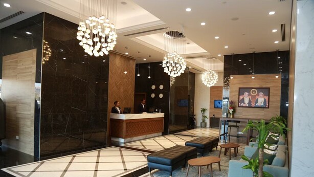 A modern hotel lobby with a reception desk, seating area, and decorative lighting. - Ayla Ibri Hotel and Mall (Ibri)