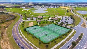 Un parcours de golf avec plusieurs greens, un court de tennis et un espace de stationnement.