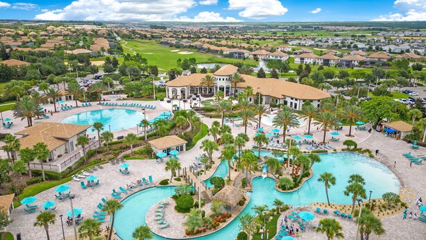 Un complexe hôtelier doté de plusieurs piscines, de palmiers et, au loin, d’un terrain de golf.