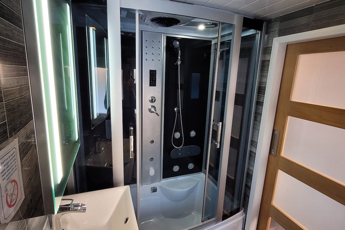 A modern bathroom with a glass-enclosed shower, a white sink, and a mirror.